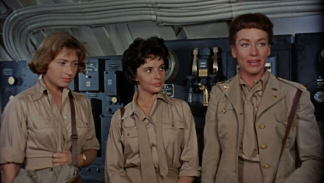 Sukellusvene ja kolme naishahmoa, jotka ovat pukeutuneet sotilasvaatteisiin, sisätiloissa.